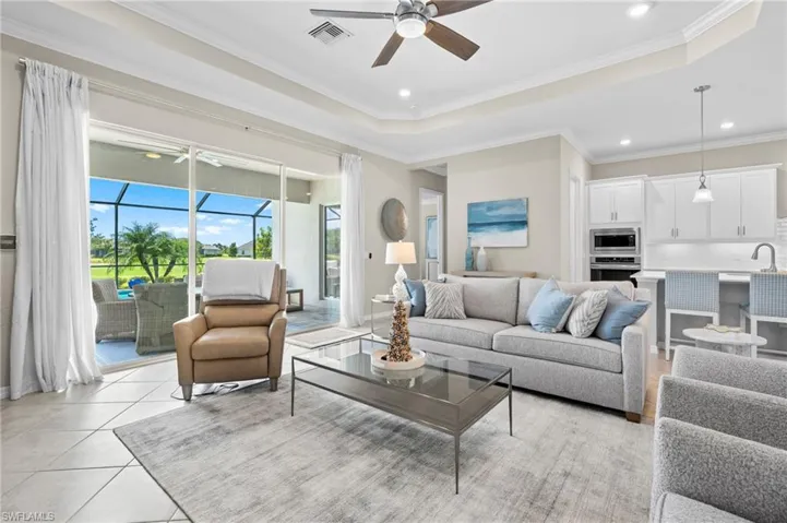 Living room featuring visible vents, ornamental molding, ceiling fan, a tray ceiling, and recessed lighting