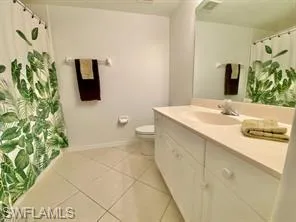 Full bathroom featuring vanity, a shower with curtain, and light tile patterned floors