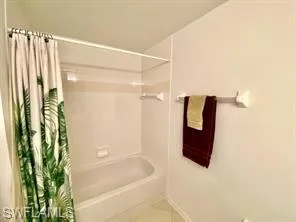 Bathroom featuring shower / tub combo with curtain and tile patterned flooring