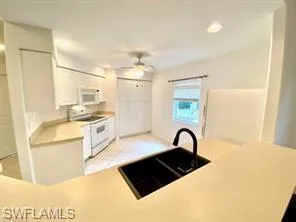 Kitchen featuring large counter bar, ample white cabinetry, light countertops, appliances, recessed lighting, and light tile patterned flooring