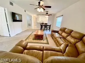Living area featuring ceiling fan Mounted TV and Lots of Sunshine with sliders to private lanai with laundry and park like view