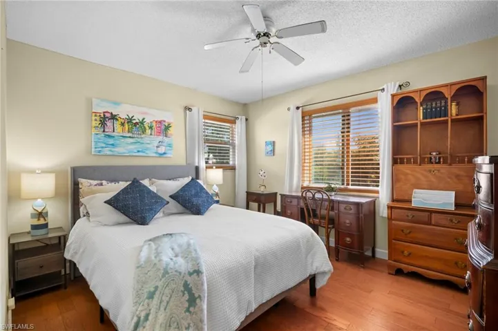 Bedroom with hardwood / wood-style flooring, a textured ceiling, and ceiling fan
