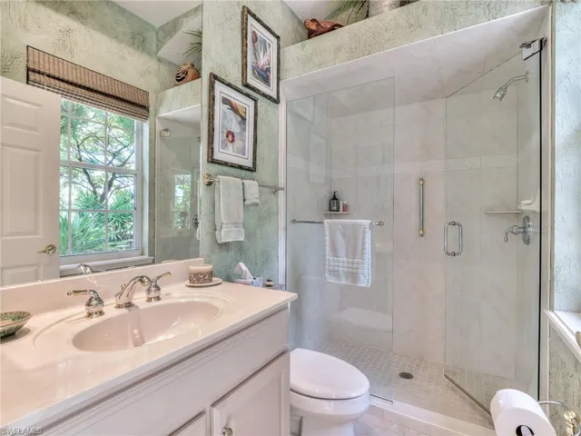 Bathroom with a shower with door, vanity, and toilet