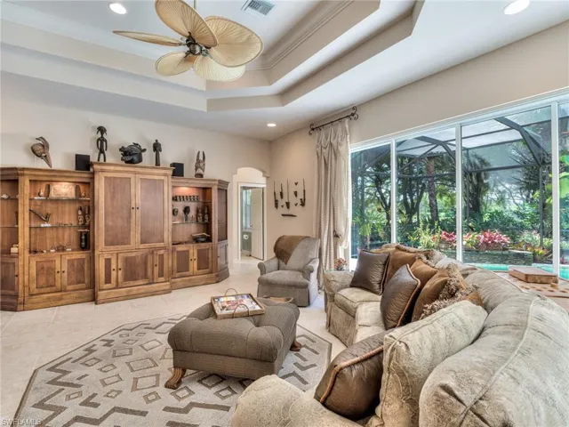 Living room featuring ceiling fan, a raised ceiling, light tile patterned flooring, and crown molding