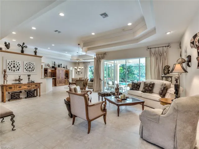 Living room featuring a raised ceiling, ornamental molding, and a chandelier