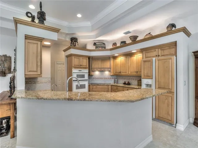 Kitchen with crown molding, kitchen peninsula, double oven, and tasteful backsplash