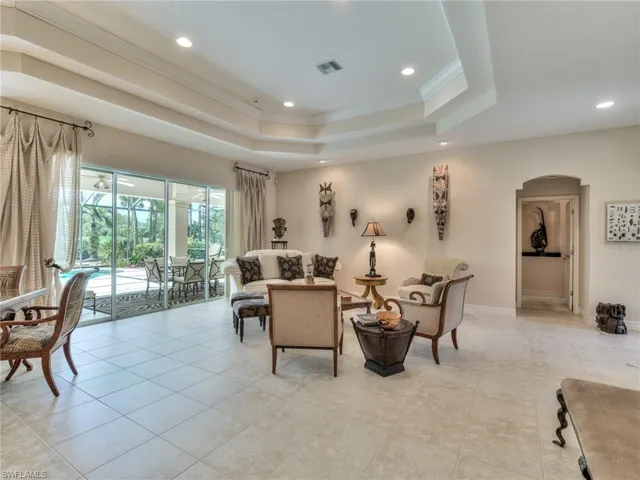 Living room featuring a raised ceiling, crown molding, and light tile patterned floors