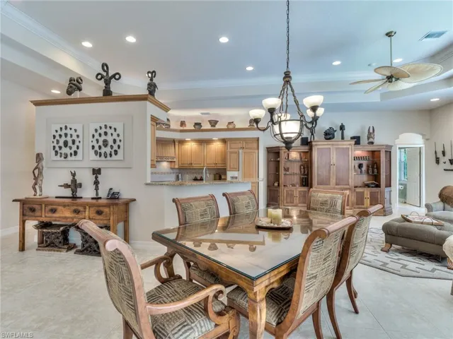 Dining room with light tile patterned flooring, ceiling fan with notable chandelier, and ornamental molding