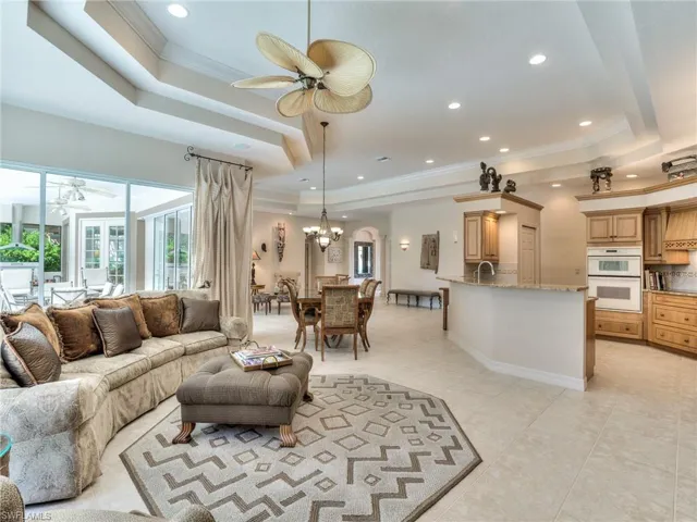 Tiled living room with ornamental molding, a tray ceiling, sink, and ceiling fan