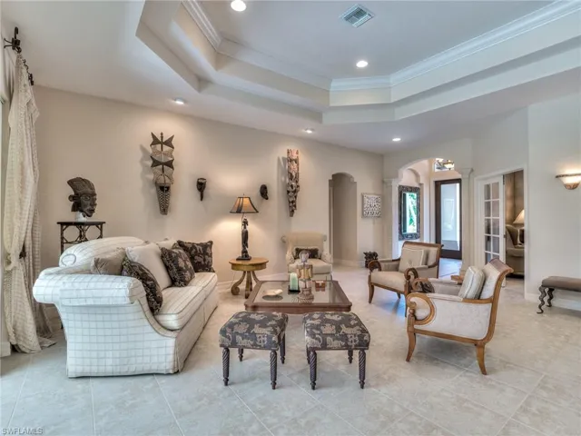 Living room with crown molding, light tile patterned floors, and a raised ceiling