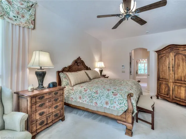 Bedroom featuring light carpet, ceiling fan, and ensuite bathroom