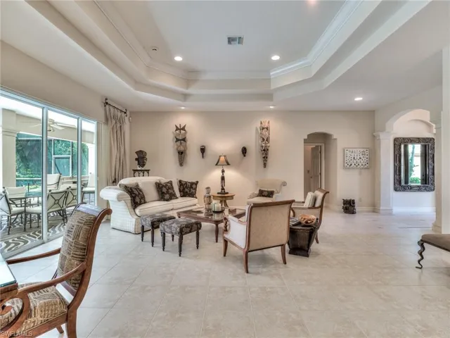 Tiled living room with ornamental molding, a tray ceiling, and a healthy amount of sunlight