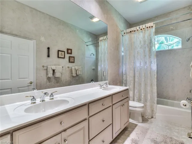 Full bathroom with vanity, shower / tub combo, toilet, and tile patterned floors