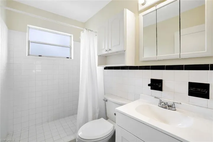Bathroom featuring a tile shower, vanity, and tile walls