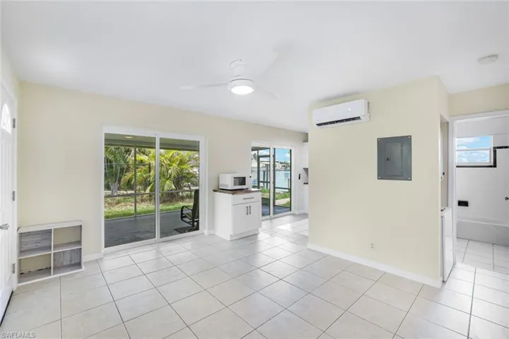 Unfurnished room featuring a wall mounted AC, electric panel, light tile patterned floors, and a ceiling fan