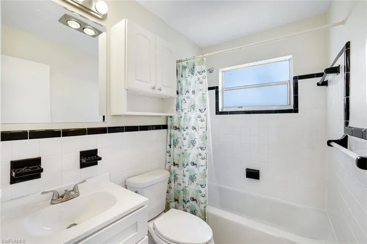 Bathroom with tile walls, shower / tub combo, and vanity