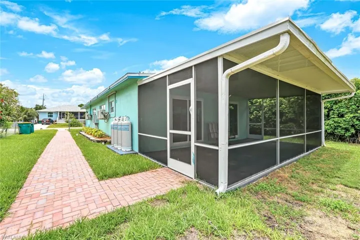 Back of property featuring a sunroom, a yard, and stucco siding