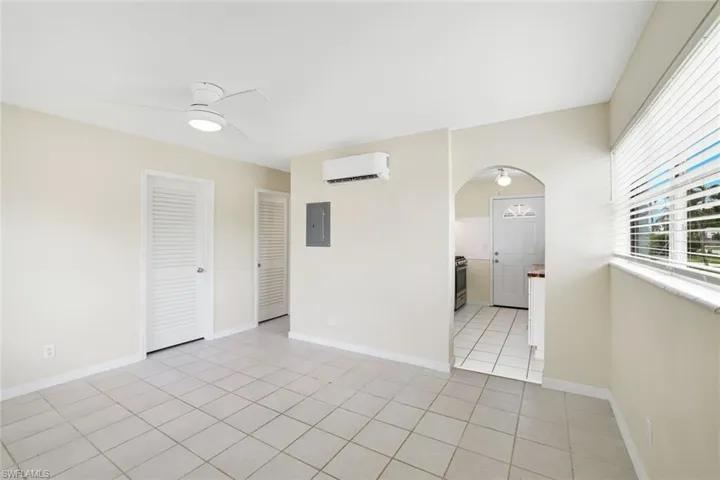 Spare room with an AC wall unit, electric panel, arched walkways, ceiling fan, and light tile patterned floors