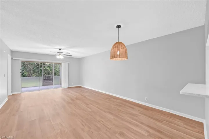 Empty room with a textured ceiling, light wood-type flooring, and ceiling fan