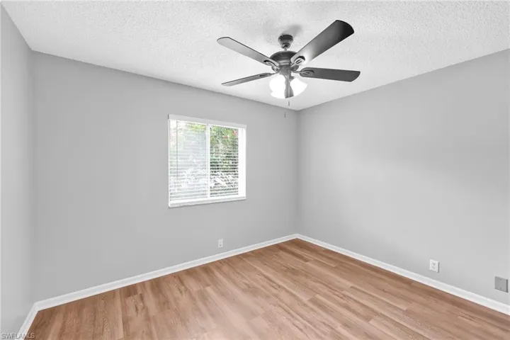 Spare room featuring light wood-type flooring, a textured ceiling, and ceiling fan