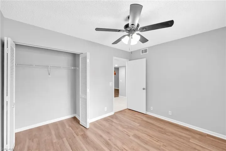 Unfurnished bedroom featuring light wood finished floors, a textured ceiling, a ceiling fan, and a closet