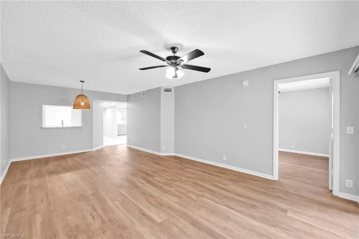 Empty room featuring a textured ceiling, light wood-style floors, and a ceiling fan