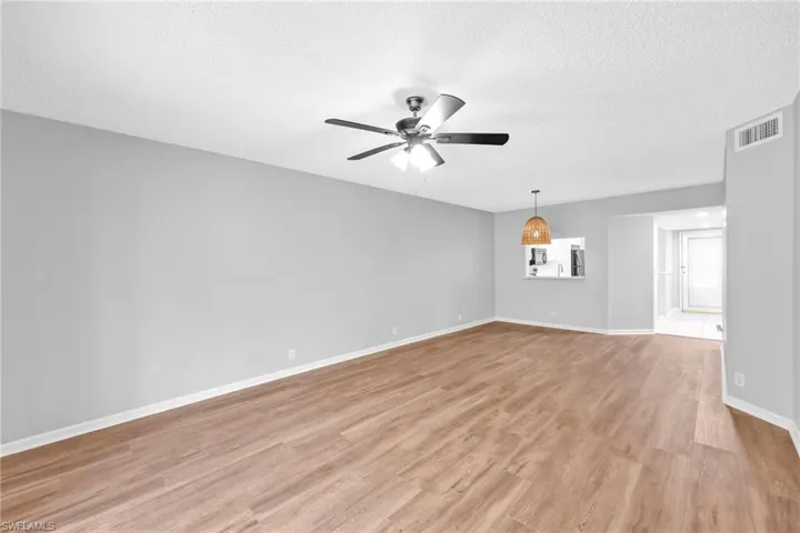 Empty room with light wood-style floors, a textured ceiling, and ceiling fan