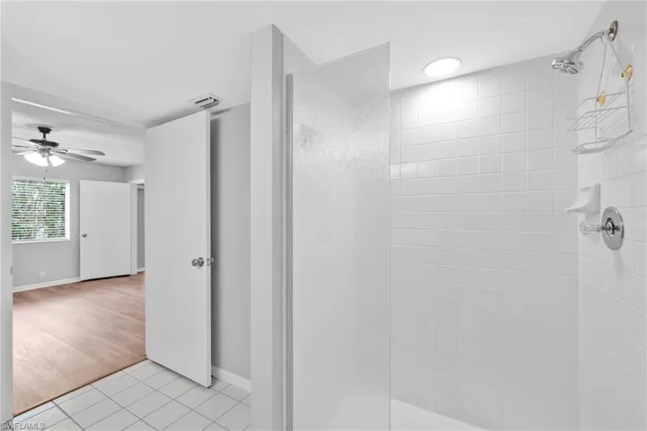 Full bath with walk in shower, light tile patterned floors, and ceiling fan