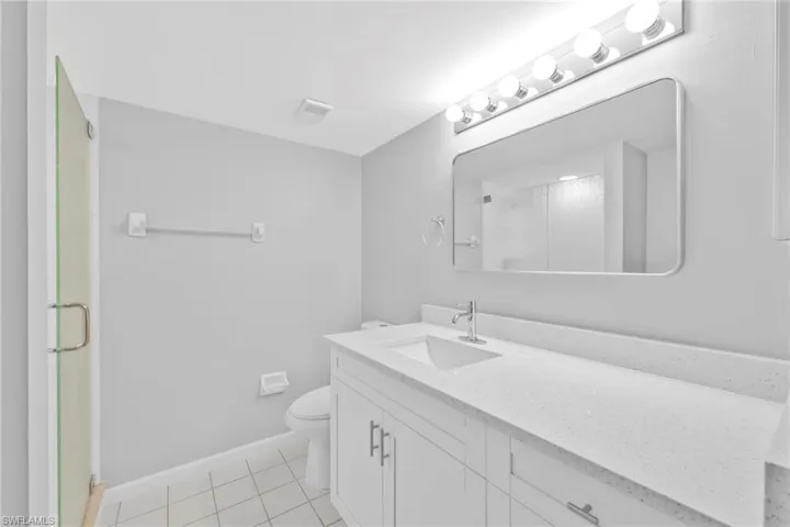 Full bath with vanity, a shower stall, and light tile patterned flooring