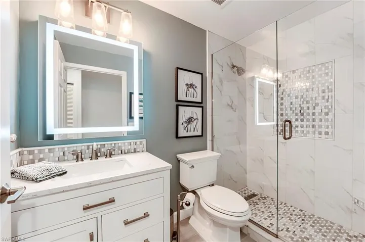 Full bath featuring a marble finish shower, vanity, and tasteful backsplash