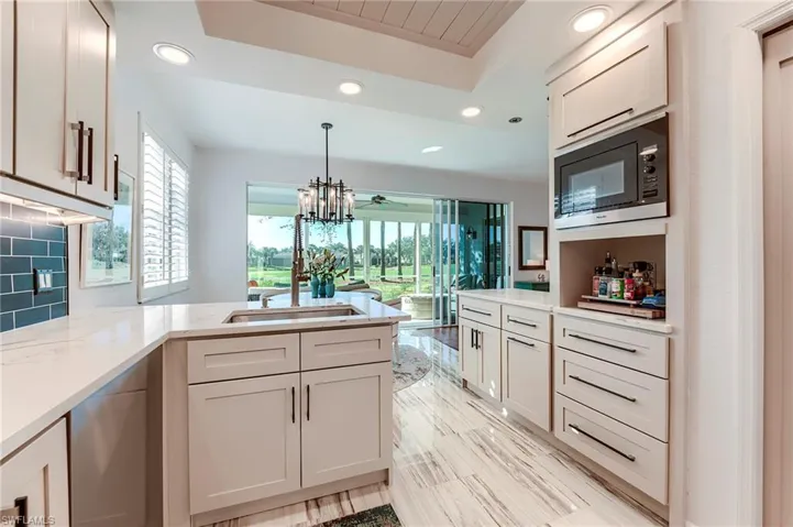 Kitchen with recessed lighting, a peninsula, plenty of natural light, built in microwave, and a chandelier