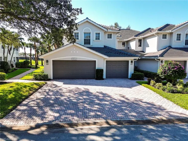 Traditional-style home with a garage, stucco siding, and decorative driveway