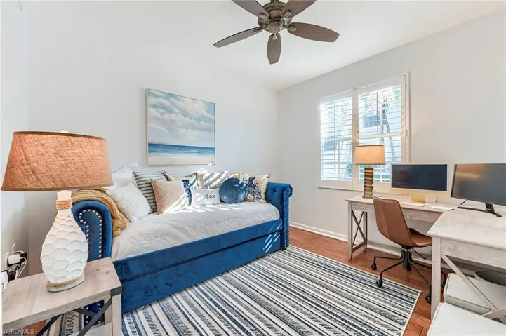Bedroom featuring wood finished floors, a ceiling fan, and an office area