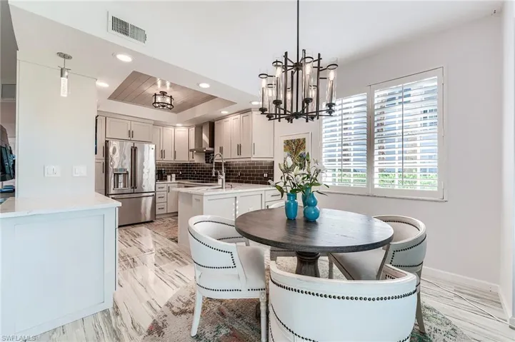 Dining space featuring a raised ceiling, recessed lighting, a chandelier, and light wood-type flooring
