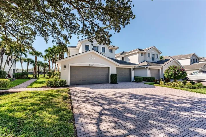 Traditional-style home with stucco siding, decorative driveway, a front lawn, and a garage