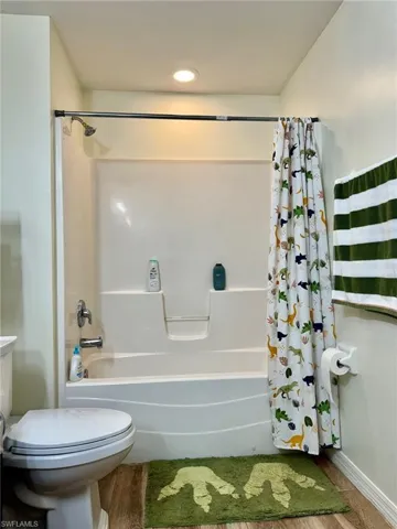 Bathroom featuring wood-type flooring, toilet, and shower / tub combo