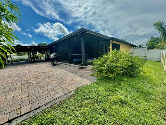 Rear view of house featuring a lawn, a patio, and a sunroom