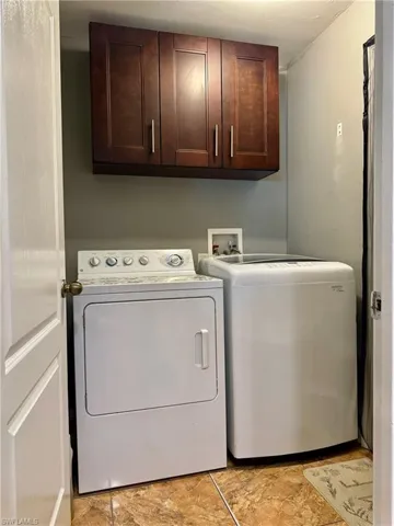 Clothes washing area featuring washer and dryer and cabinets