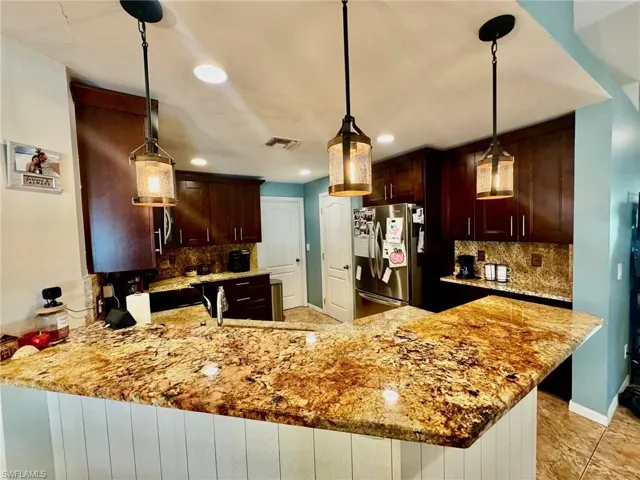 Kitchen featuring hanging light fixtures and light stone counters