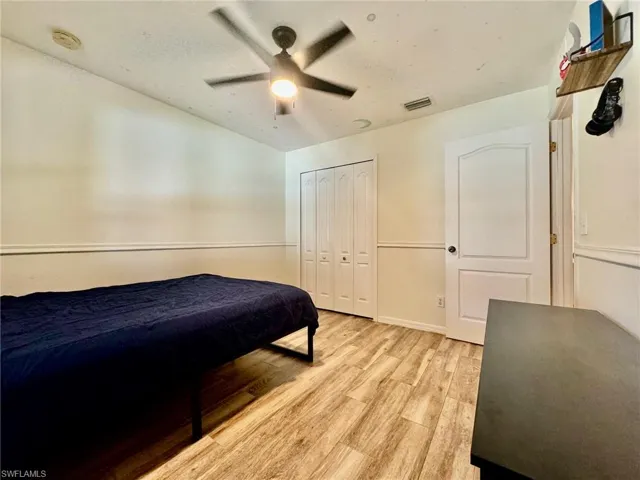 Bedroom with ceiling fan, a closet, and light wood-type flooring