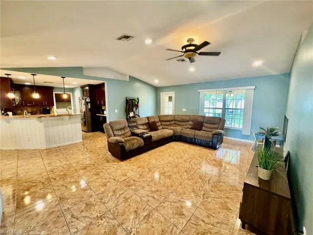 Living room featuring ceiling fan and vaulted ceiling