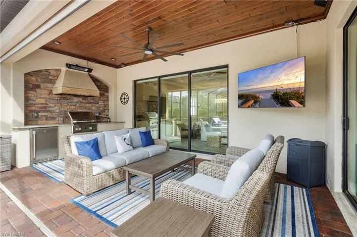 Covered patio with a wood-plank ceiling, ceiling fan, and brick-style flooring
