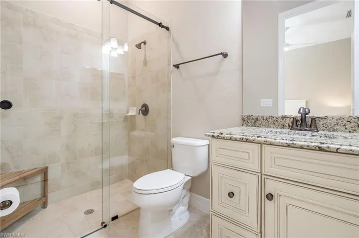 Glass-enclosed shower with subway tile surround and dark bronze fixtures