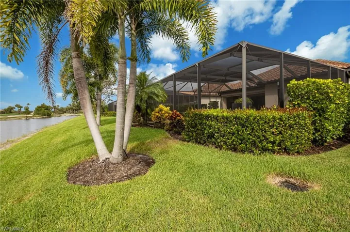 Screened enclosure over a patio area, mature tropical landscaping, and a water feature