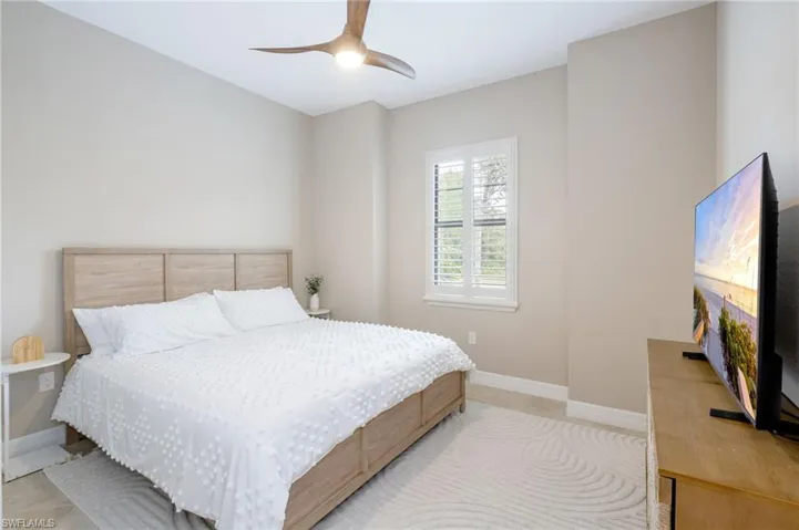 Window with plantation shutters, ceiling fan with integrated lighting, and light-toned walls
