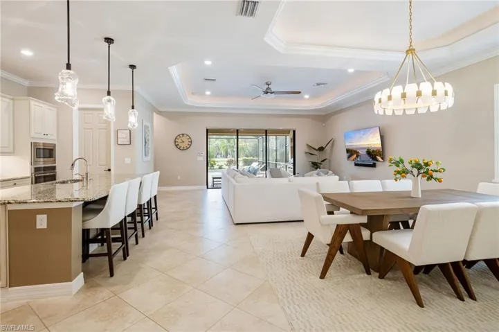 Open concept living area with tray ceiling, recessed lighting, and tile flooring