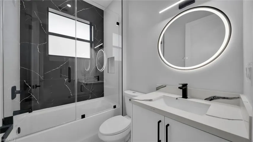 Full bath with vanity and bath / shower combo with glass door
