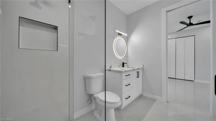 Bathroom with vanity, ceiling fan, and a stall shower