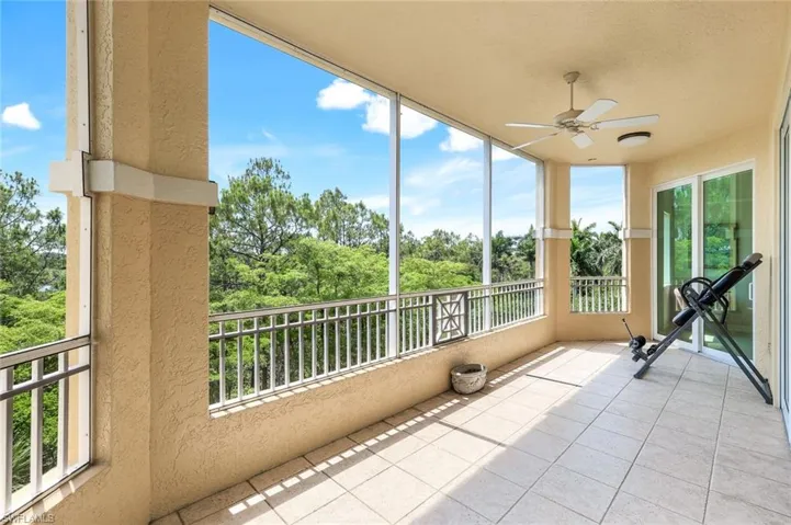 Unfurnished sunroom with a textured wall, tile patterned flooring, and view of wooded area