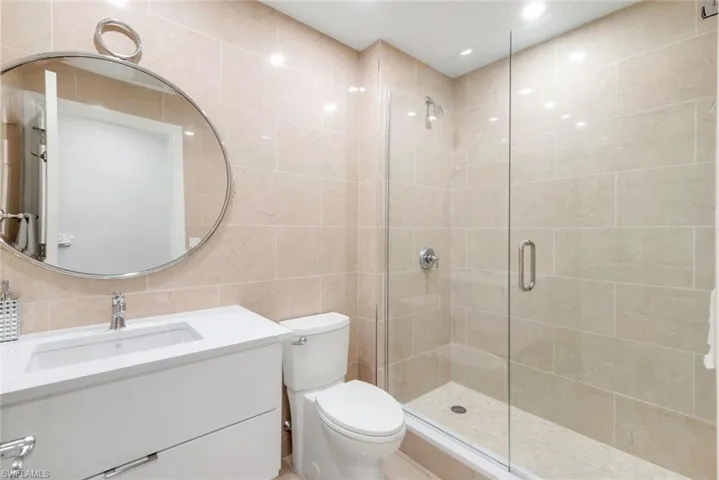 Full bath with a shower/tub combo, vanity, tile walls, and toilet